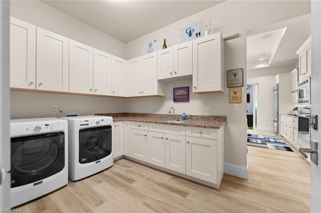9172 Mercato Lane Naples, FL 34108 - Photo 25 of 29 Laundry area featuring light wood-type flooring, washing machine and clothes dryer, and cabinet space