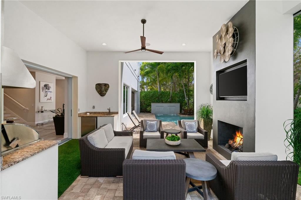 9172 Mercato Lane Naples, FL 34108 - Photo 29 of 29 View of patio / terrace featuring a ceiling fan, an outdoor kitchen and area to lounge, and a lit fireplace