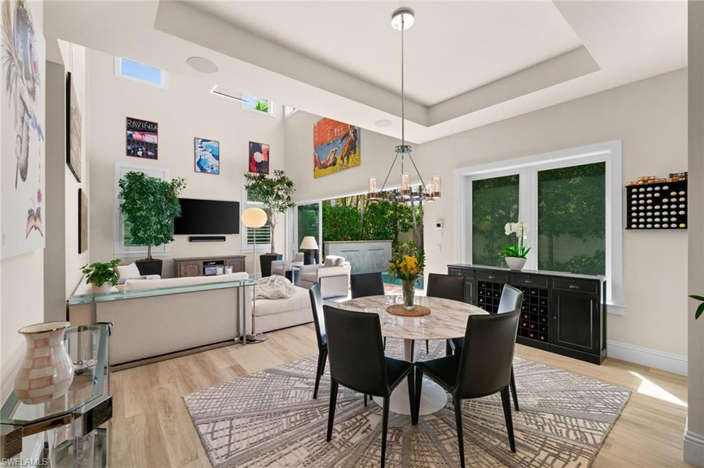 9172 Mercato Lane Naples, FL 34108 - Photo 9 of 29 Dining area with suspended lighting, light wood-style floors, and a raised ceiling
