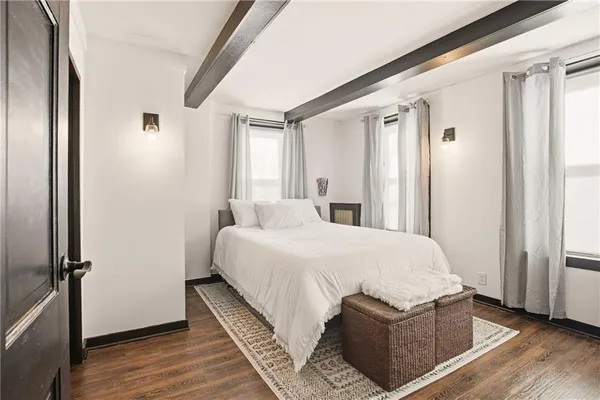 a bedroom with a bed wooden floor and window