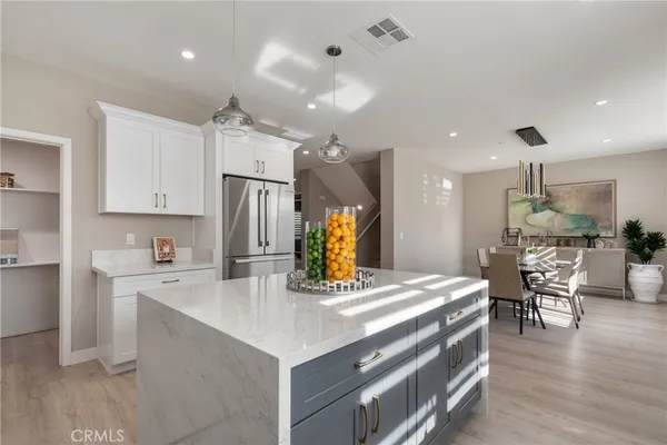 a kitchen with stainless steel appliances kitchen island granite countertop a table chairs and a refrigerator