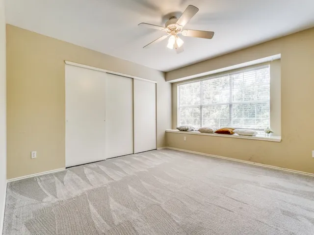 an empty room with chandelier fan and windows