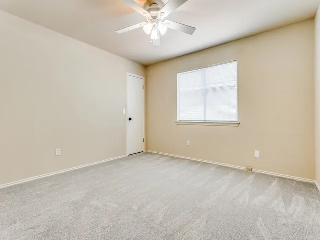 an empty room with a window and a ceiling fan