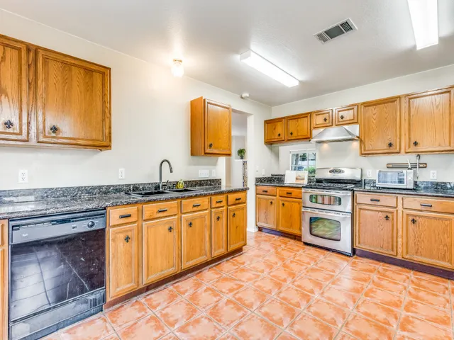 a kitchen with stainless steel appliances granite countertop a stove sink and cabinets