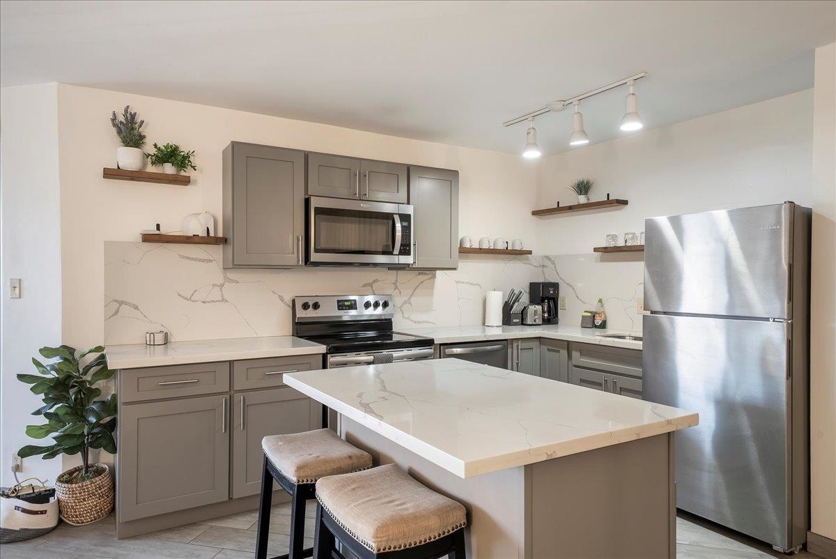 938 South Kihei Road, Unit 423 Kihei, HI 96753 - Photo 7 of 50 a kitchen with a refrigerator a sink a stove cabinets and wooden floor
