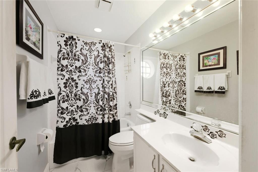 209 Countryside Drive Naples, FL 34104 - Photo 26 of 50 Bathroom with vanity, shower / bath combo with shower curtain, and light marble finish flooring