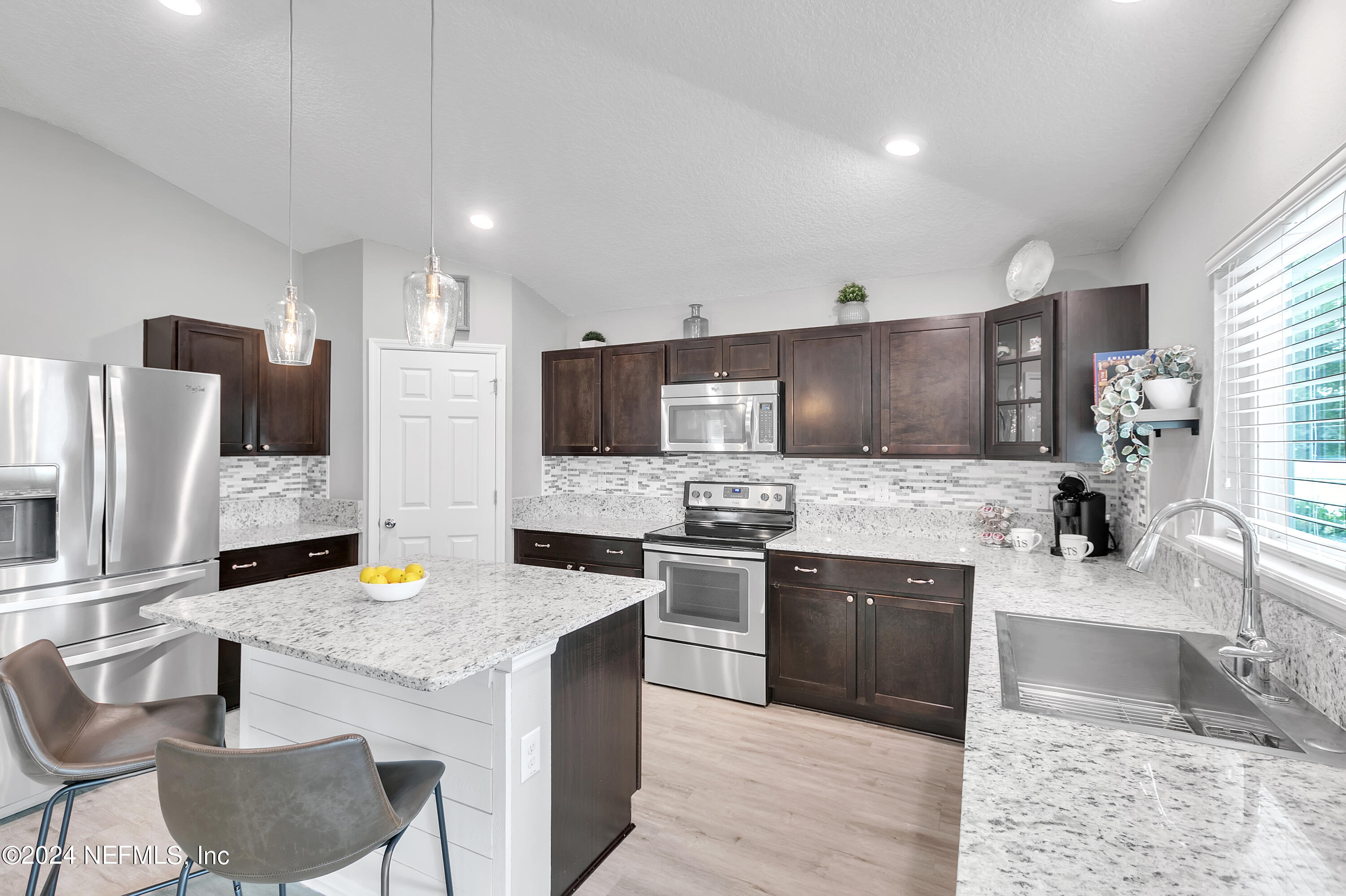 a kitchen with stainless steel appliances kitchen island granite countertop a sink and a stove top oven with wooden floor