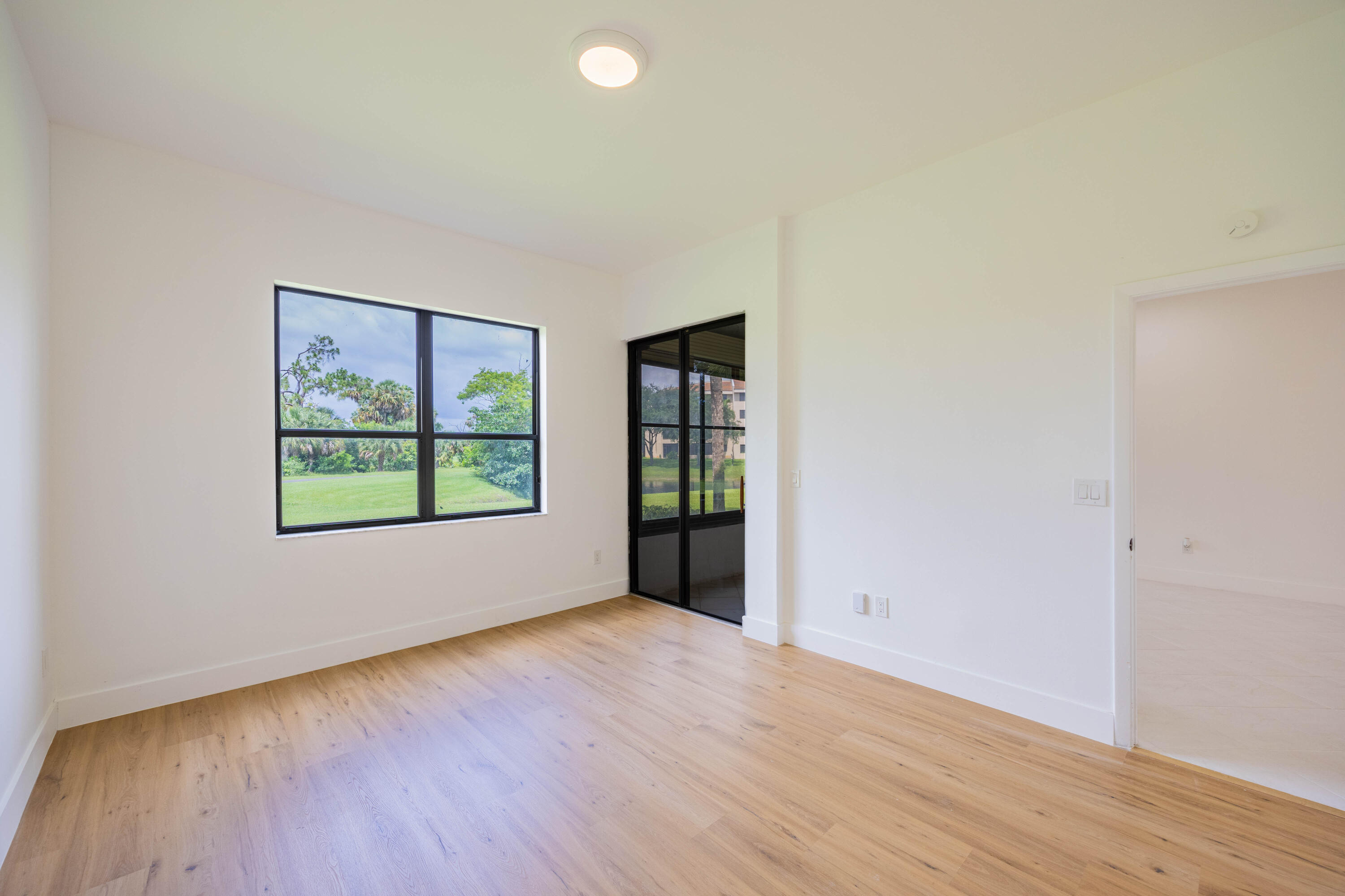 7520 La Paz Boulevard, Unit 104 Boca Raton, FL 33433 - Photo 24 of 56 an empty room with wooden floor and windows