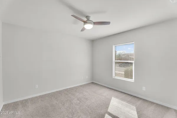 an empty room with windows and ceiling fan view