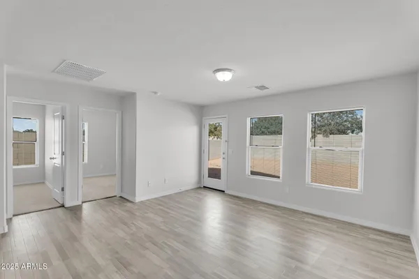 an empty room with wooden floor and windows