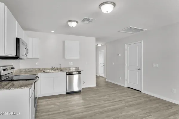 a kitchen with granite countertop a sink cabinets and wooden floor