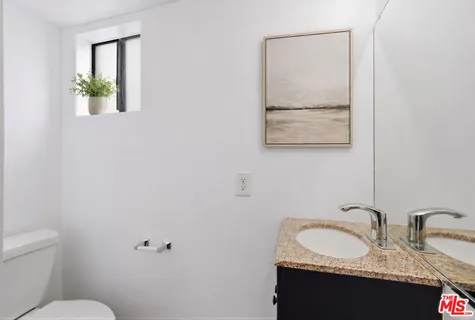 a bathroom with a granite countertop sink and a toilet