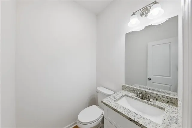 a bathroom with a granite countertop sink mirror vanity and toilet