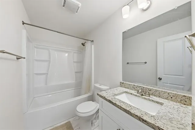 a bathroom with a granite countertop sink mirror vanity and toilet
