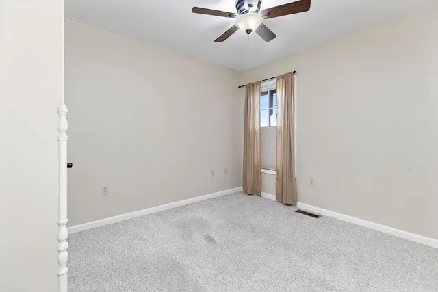 an empty room with a chandelier fan and windows