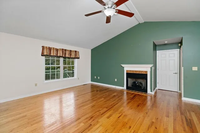 an empty room with wooden floor a fireplace and windows