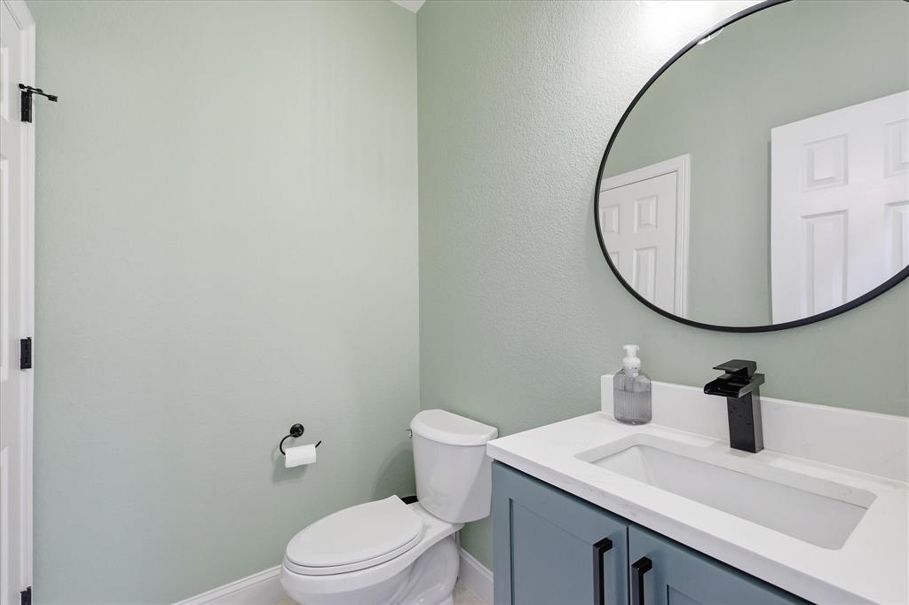 430 Ridgecrest Place Sanger, TX 76266 - Photo 26 of 40 Bathroom featuring a modern vanity with a white countertop, integrated sink, matte black faucet, and a circular mirror with a black frame