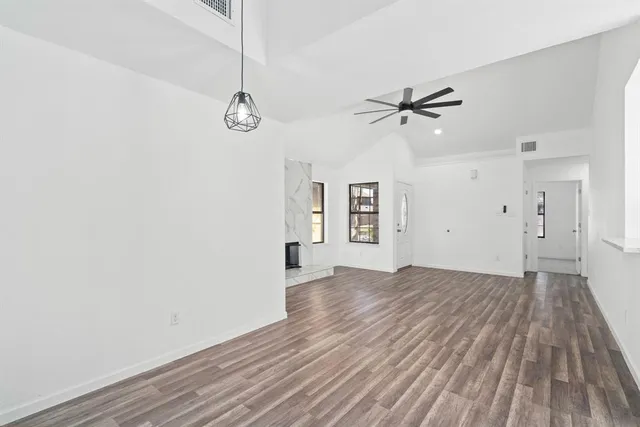 an empty room with wooden floor ceiling fan and windows