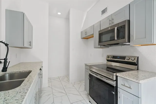 a kitchen with stainless steel appliances granite countertop a sink and a stove