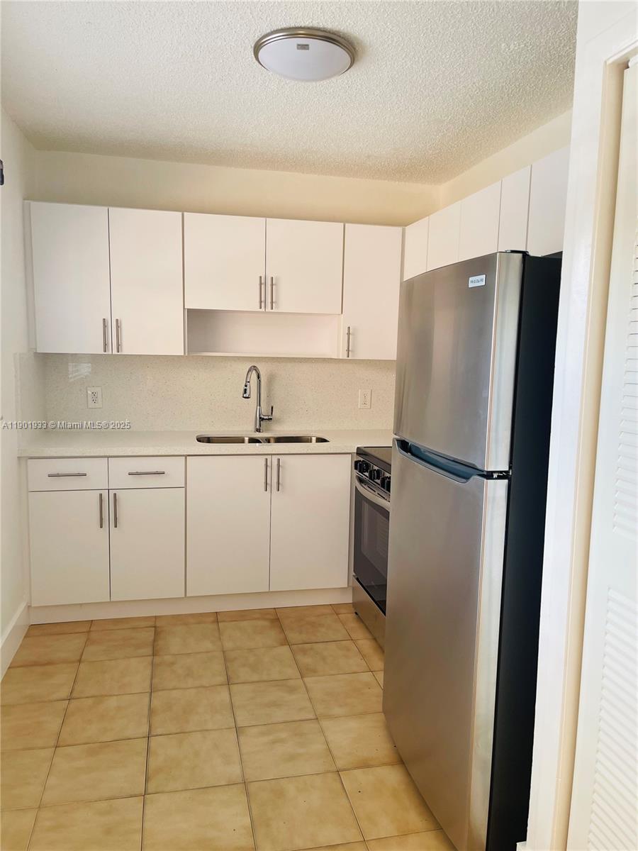 61 West 23rd Street, Unit 104 Hialeah, FL 33010 - Photo 9 of 17 a kitchen with a refrigerator sink and cabinets