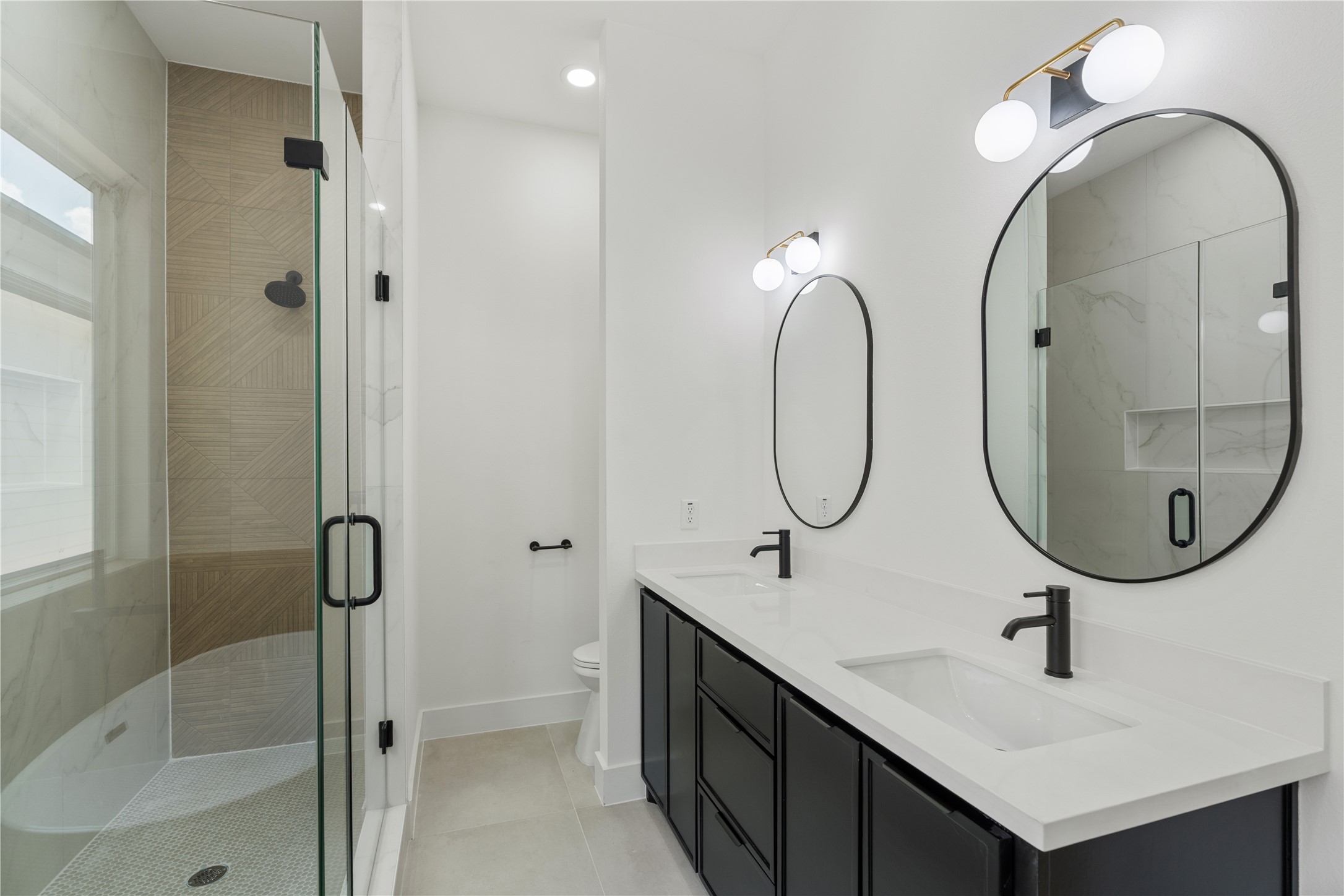 7319 Laura Koppe Road Houston, TX 77028 - Photo 19 of 42 Elegant bathroom featuring a spacious glass-enclosed shower, dual vanity with sleek black fixtures, and modern lighting.