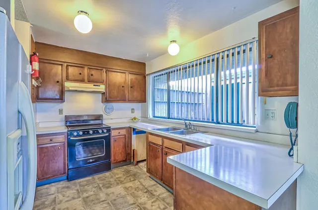 a kitchen with stainless steel appliances granite countertop a sink stove and wooden cabinets