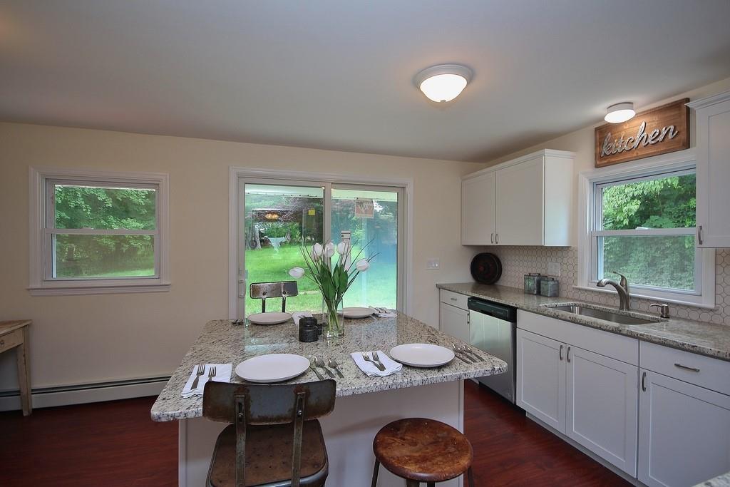 Fully equipped kitchen with granite counters, center island (eat in), laminate floors, sliding door to huge yard (unfurnished - staged for photos)