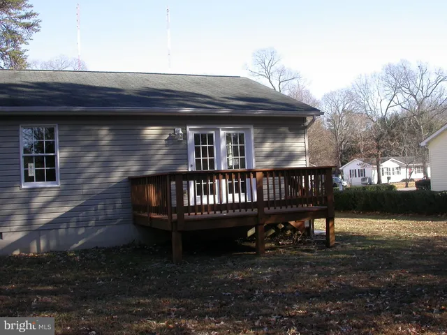 a small house with a wooden deck and furniture