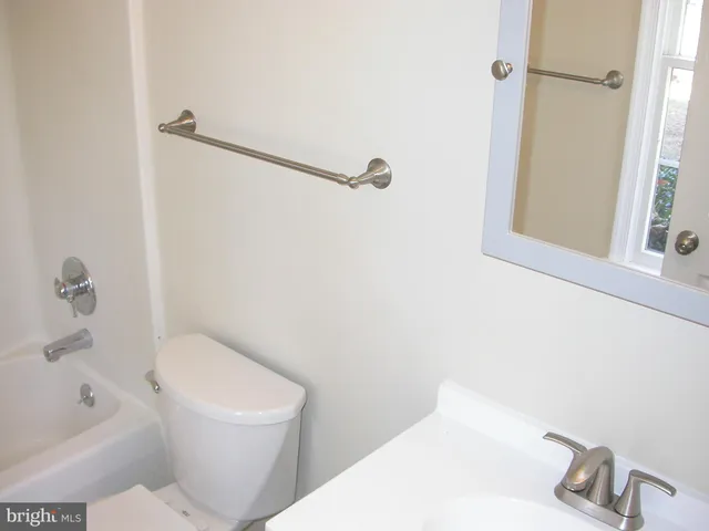 a white toilet sitting next to a bath tub