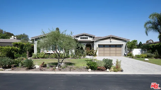 a front view of a house with a yard and potted plants