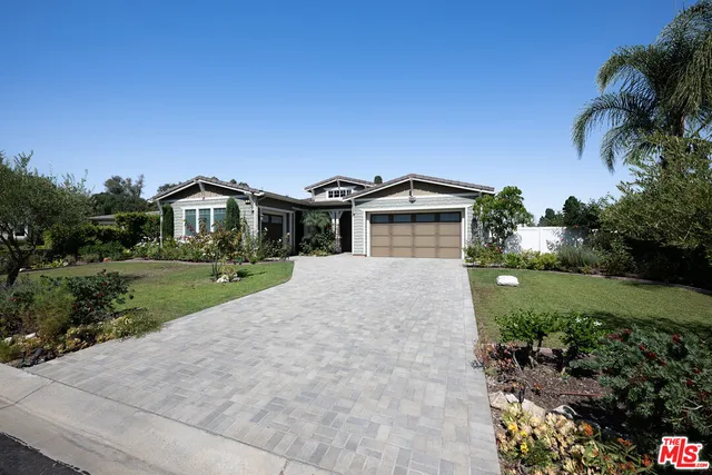 a front view of a house with a yard and potted plants