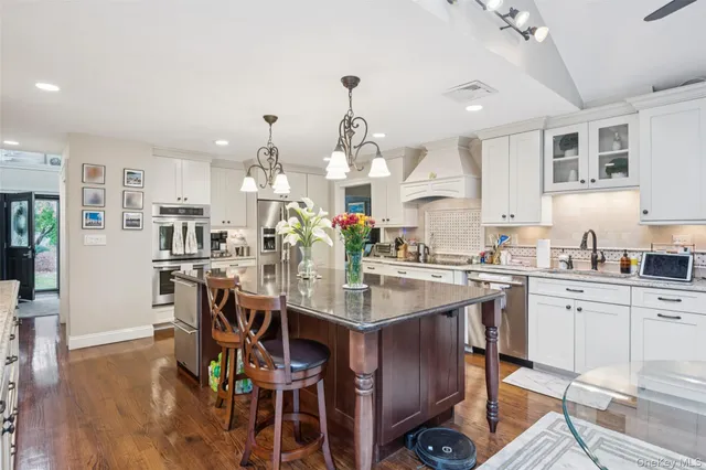 a kitchen with stainless steel appliances kitchen island granite countertop a table chairs sink and cabinets