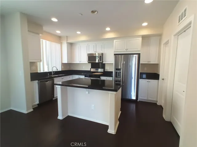 a kitchen with stainless steel appliances granite countertop a refrigerator and a sink
