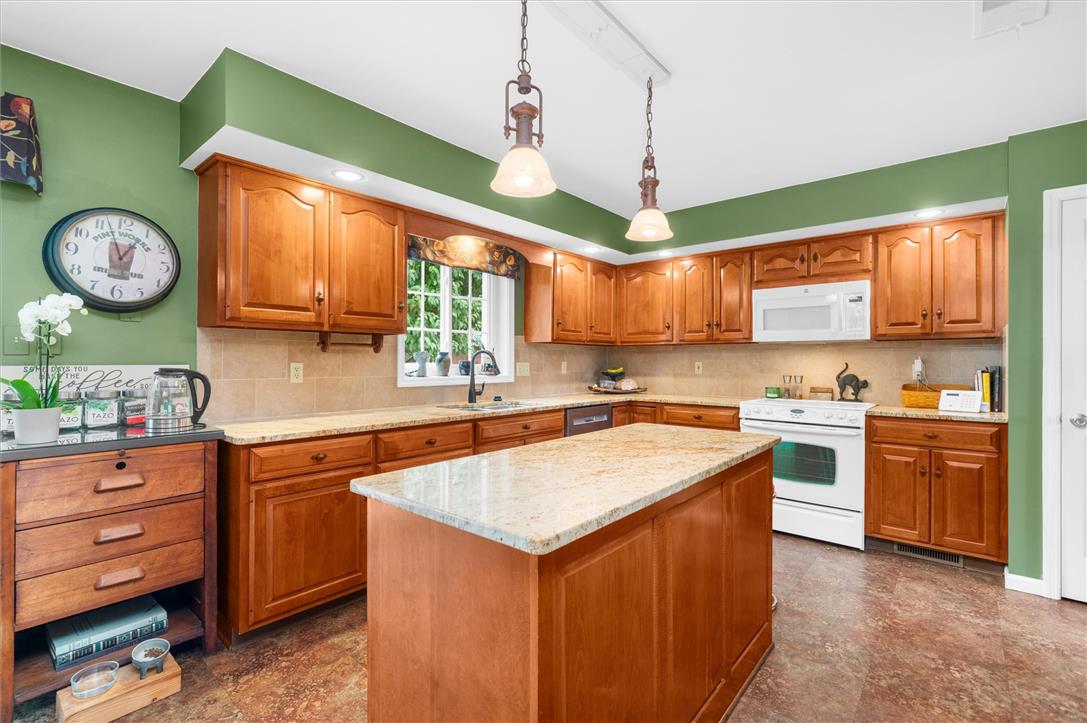 5616 Snowdrift Road Orefield, PA 18069 - Photo 6 of 36 A well-appointed kitchen showcasing rich wooden cabinetry and stone counters, illuminated by pendant lights.