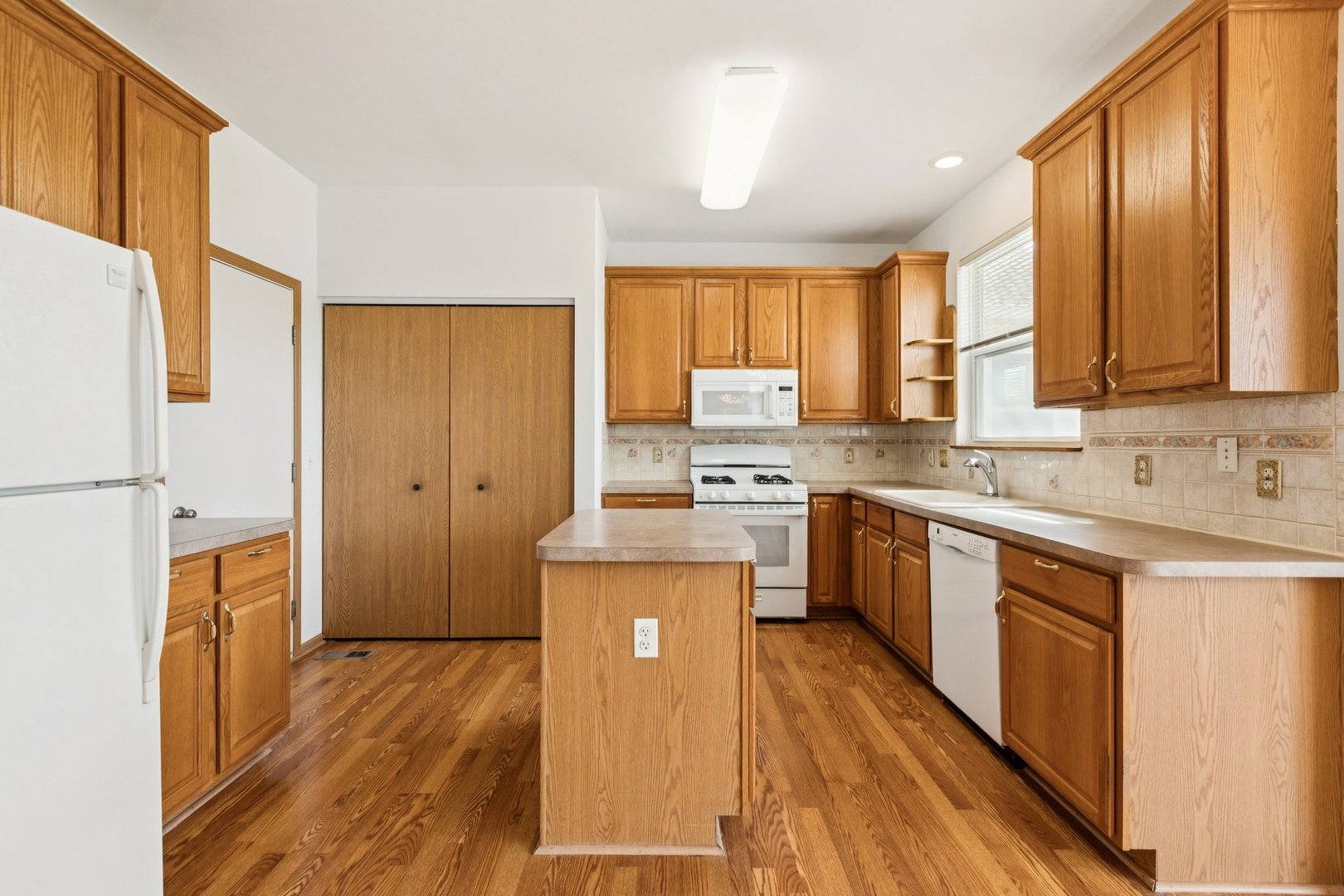 647 South Cadillac Circle Romeoville, IL 60446 - Photo 13 of 38 a kitchen with a sink appliances cabinets wooden floor and a window