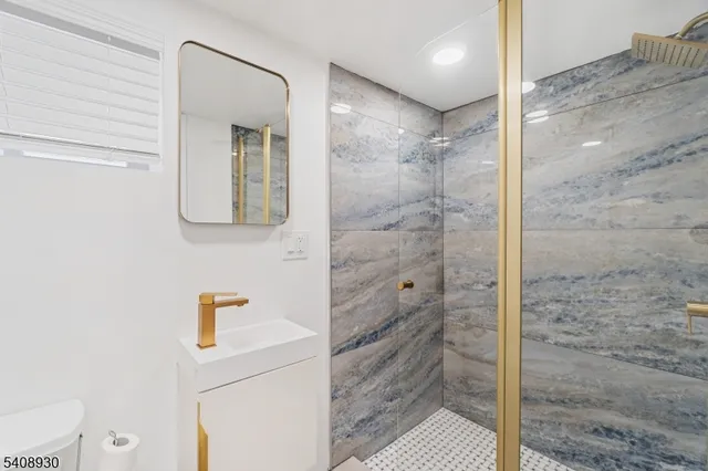 a bathroom with a granite countertop bathtub shower sink vanity and toilet