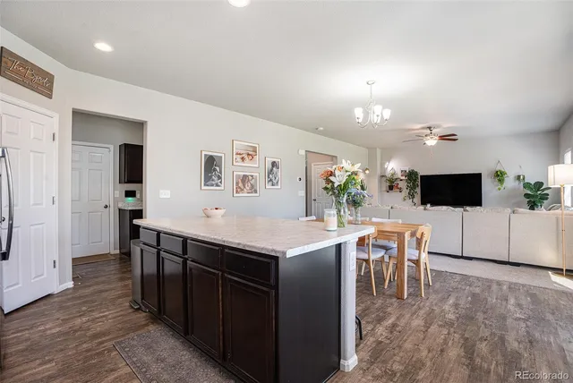 a kitchen with stainless steel appliances kitchen island granite countertop a refrigerator a stove a sink dishwasher and a microwave with wooden floor