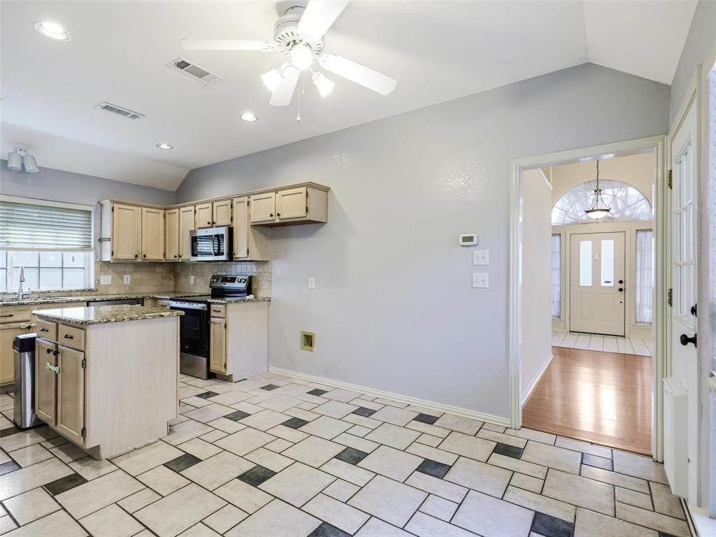 7836 Tournament Road Frisco, TX 75035 - Photo 8 of 23 Kitchen with vaulted ceiling, recessed lighting, ceiling fan, tile flooring, and a kitchen island with stone countertops