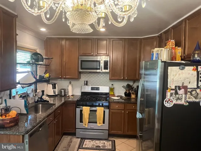 a kitchen with stainless steel appliances granite countertop a refrigerator a stove and a sink