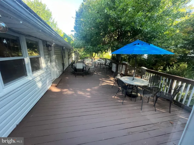 a view of a roof deck with table and chairs under an umbrella with wooden floor