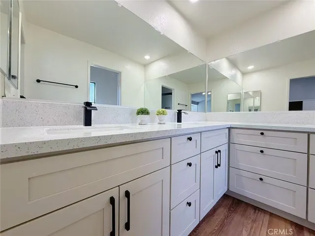 a bathroom with a granite countertop double vanity sink and mirror