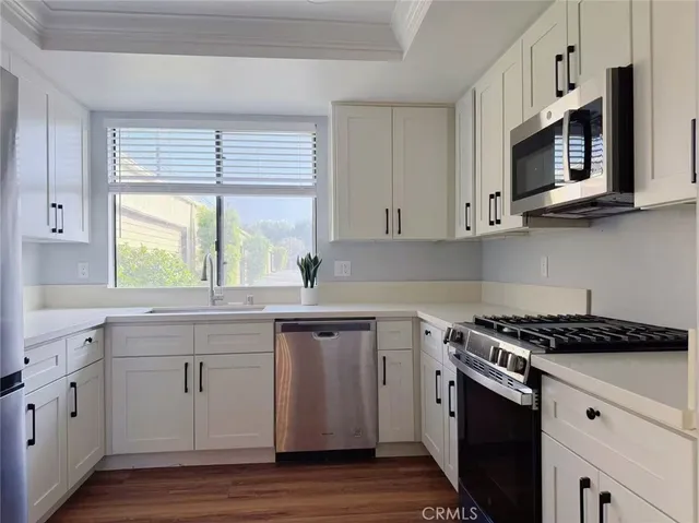 a kitchen with stainless steel appliances granite countertop white cabinets a sink and a stove