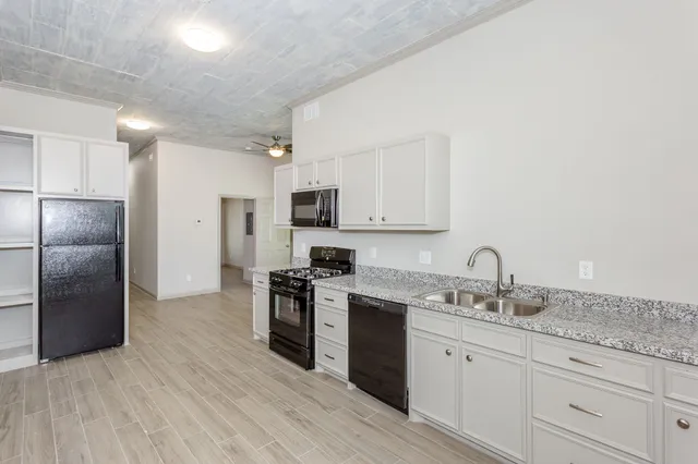 a kitchen with granite countertop a refrigerator stove and sink