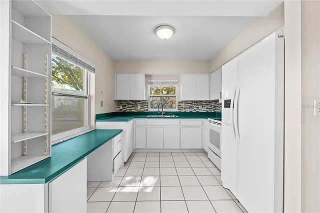 a kitchen with granite countertop a refrigerator and white cabinets