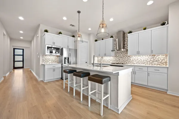 a kitchen with a sink dishwasher and white cabinets with wooden floor