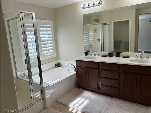 a bathroom with a double vanity sink a mirror a bathtub and next to a window