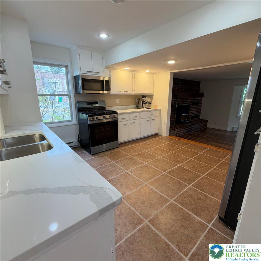 5111 Vera Cruz Road Emmaus, PA 18049 - Photo 20 of 44 Tiled floors and stone countertops define this kitchen overlooking the fireplace room.