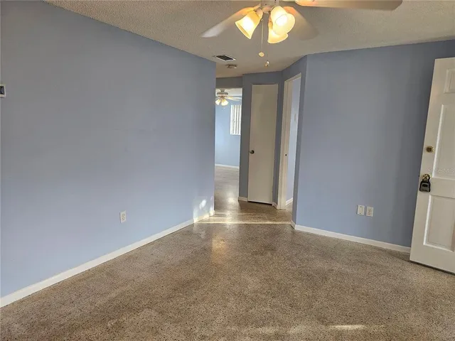 an empty room with a chandelier fan and windows