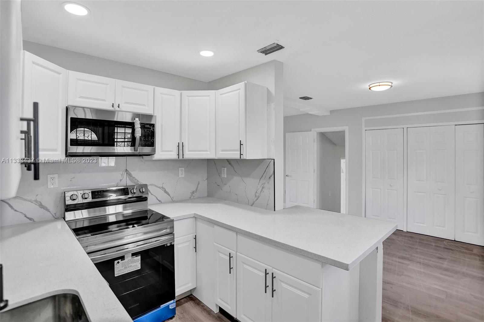 1101 Northwest 147th Street Miami, FL 33168 - Photo 11 of 45 a kitchen with sink a microwave and cabinets