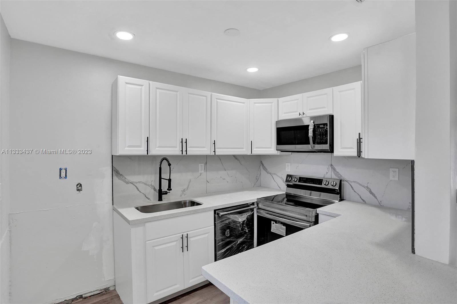 1101 Northwest 147th Street Miami, FL 33168 - Photo 13 of 45 a kitchen with stainless steel appliances a stove a sink a microwave and cabinets